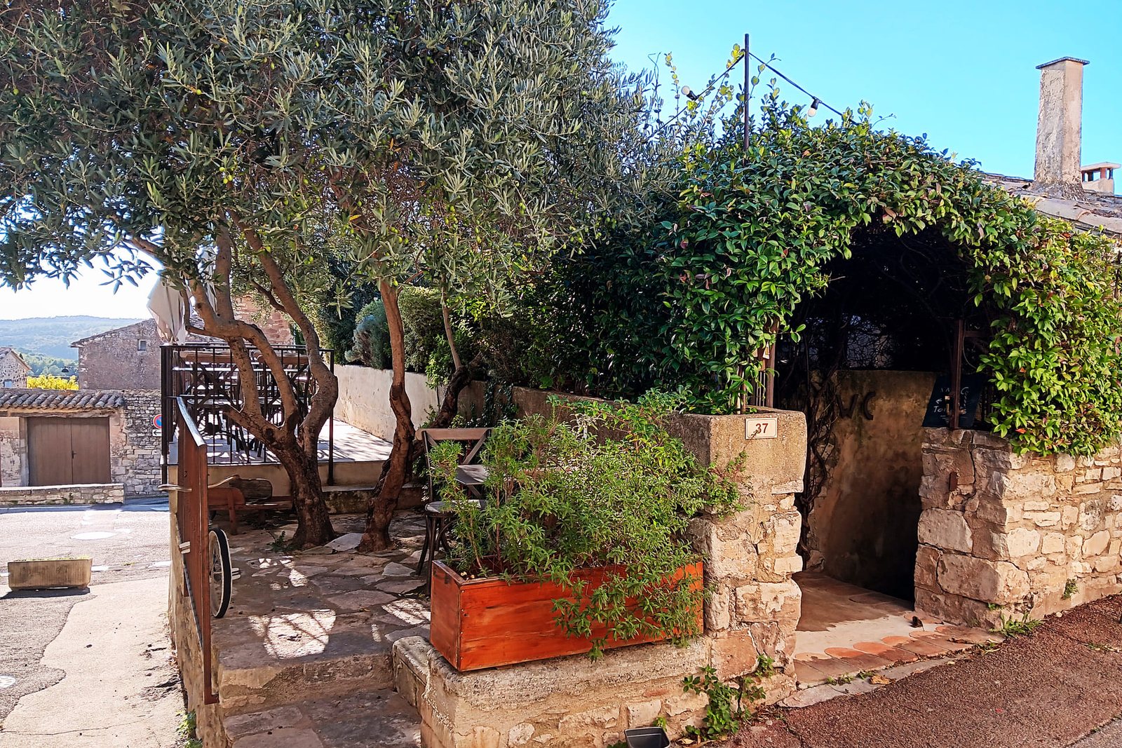 The stone entrance and leafy terrace of Le Crillon in Murs.