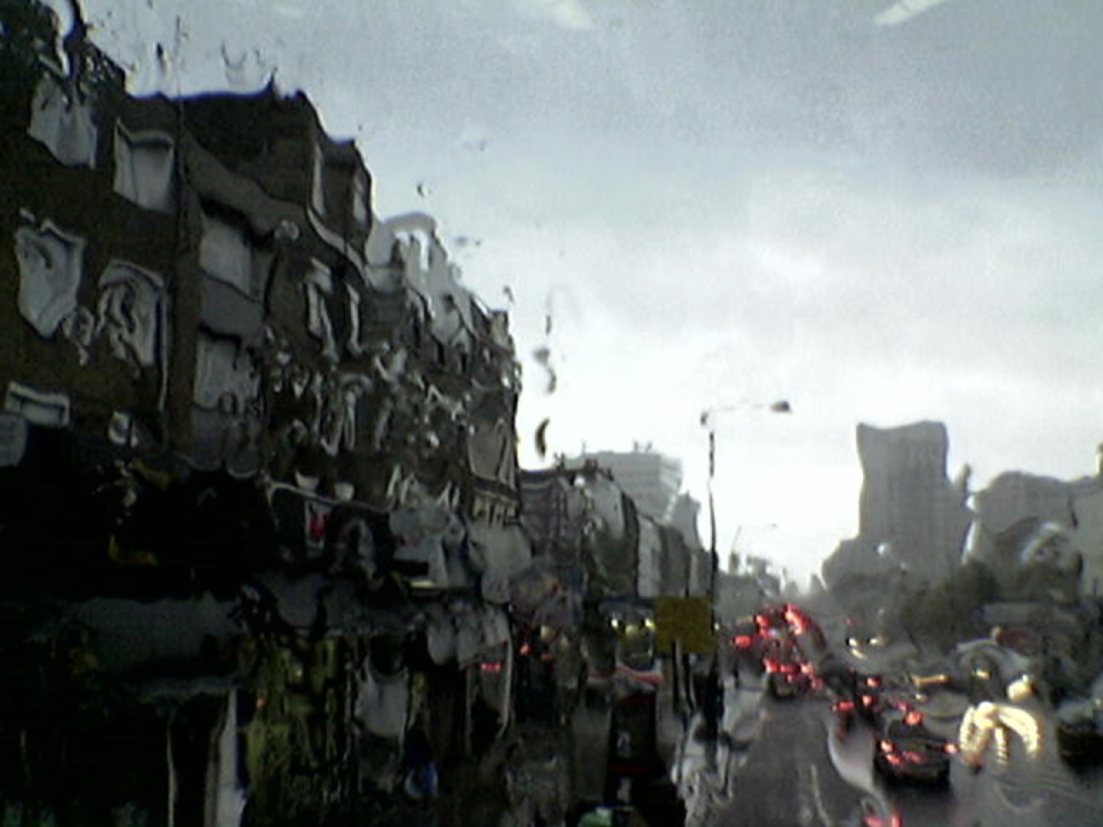 A city street and traffic distorted through rainwater on a window
