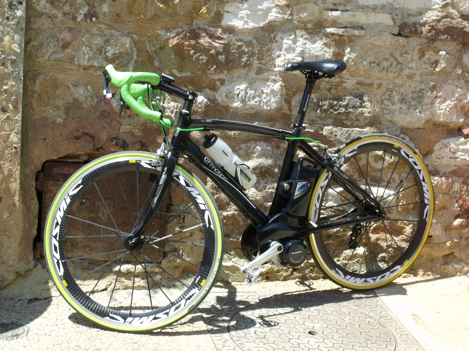 A bright racing bicycle leaning against an old stone wall in Roussillon