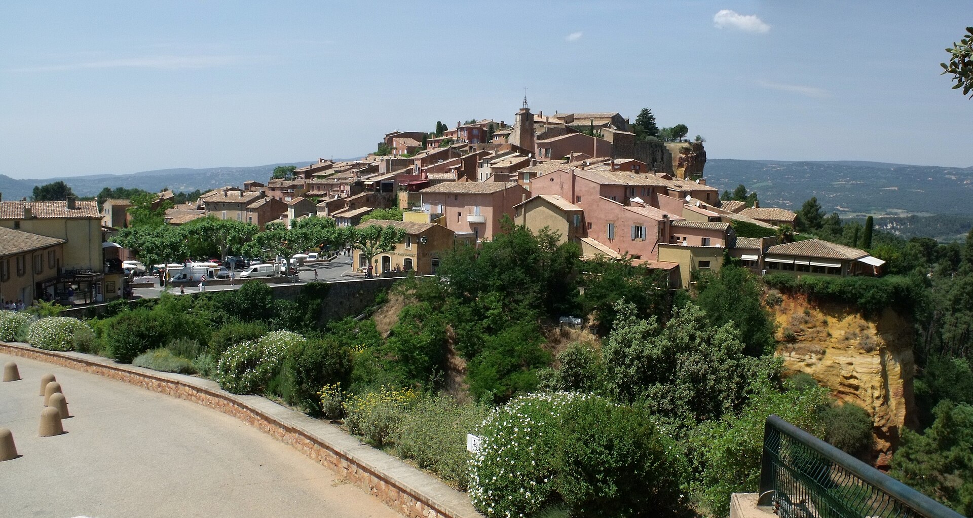 Wide view of Roussillon, its planted viewpoint and ochre cliff