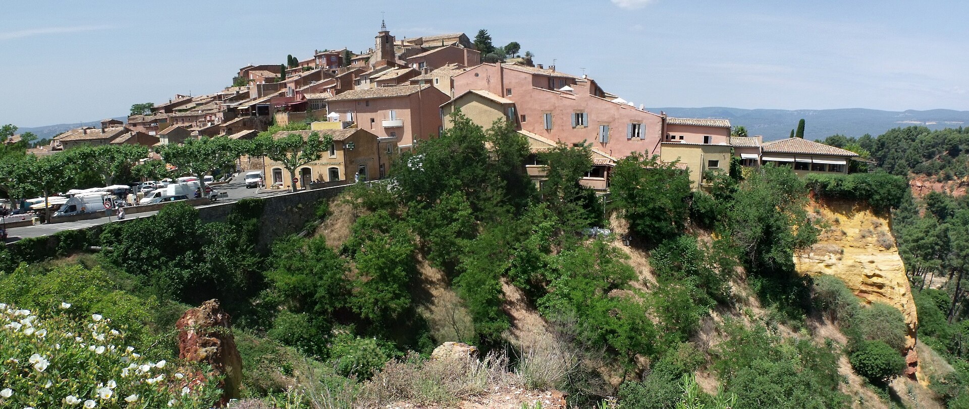 A broad panorama of Roussillon rising above its ochre cliff