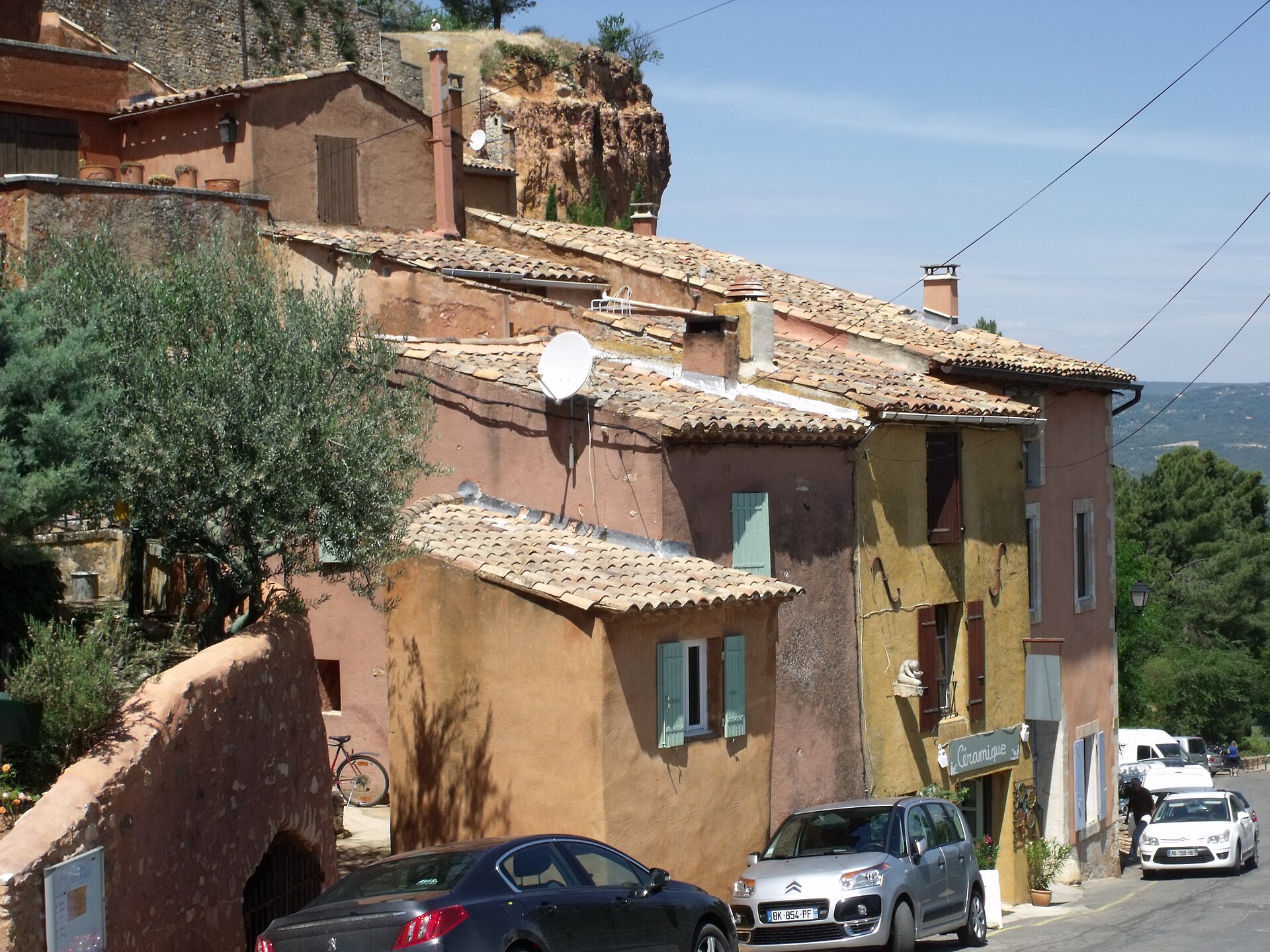 Ochre houses and tiled roofs climbing a sloping Roussillon street